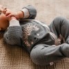Grauer Baby-Strampler mit Füßen und Igelstickerei